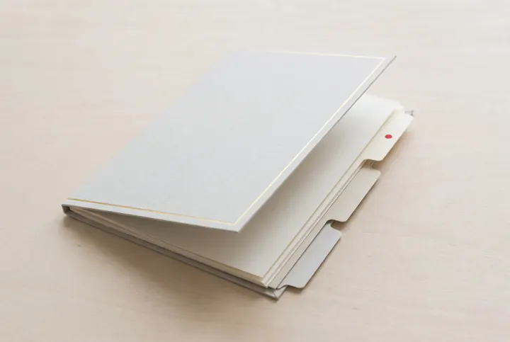 Pale grey folder holding blank sheets with unlabeled index tabs